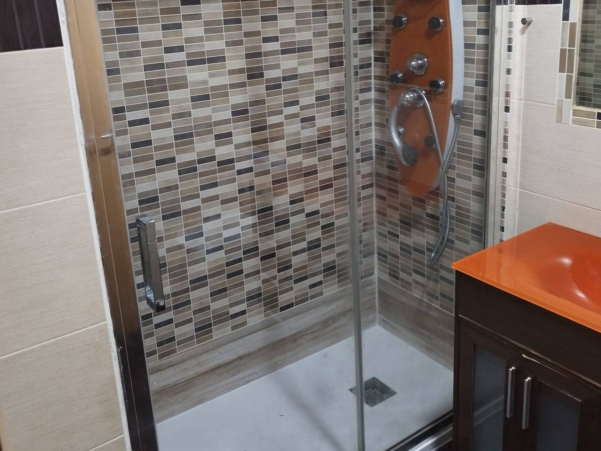 Baño con plato de ducha nuevo, mampara de vidrio y pared de mosaico