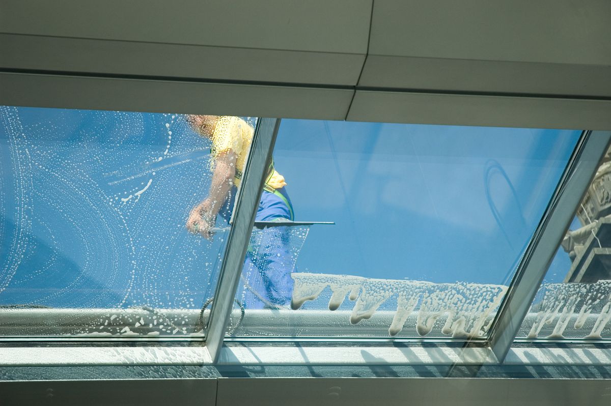 Operario limpiando desde el exterior los cristales de la cubierta de un edificio